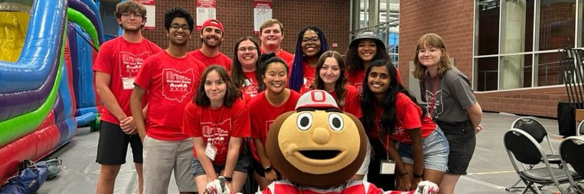 A group of OWL Coordinators stand around a sitting Brutus Buckeye